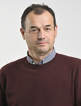 © Johannes Zinner Auf dem Foto ist Robert Müller zu sehen, er hat einen weinroten Pullover an, braune kurze Haare und ist vor einem hellen Hintergrund.