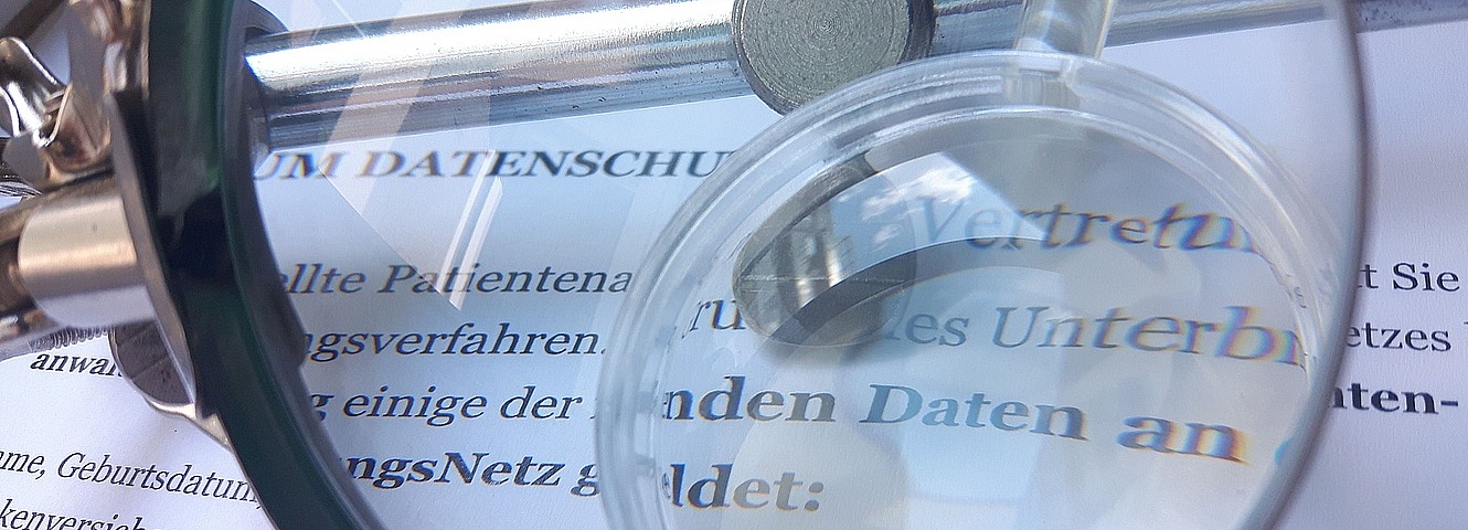 Foto: Lupe über einem Papier zum Datenschutz