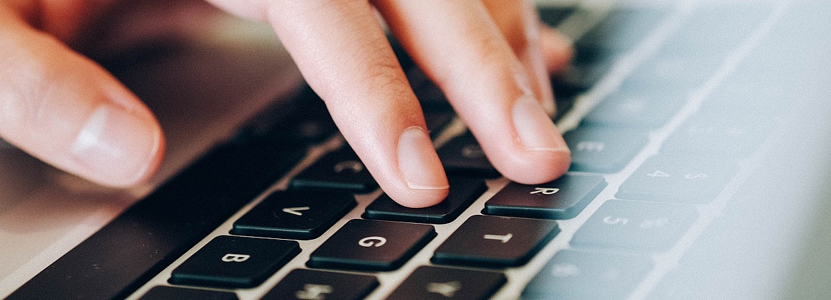 Foto: Hand auf schwarzer Tastatur