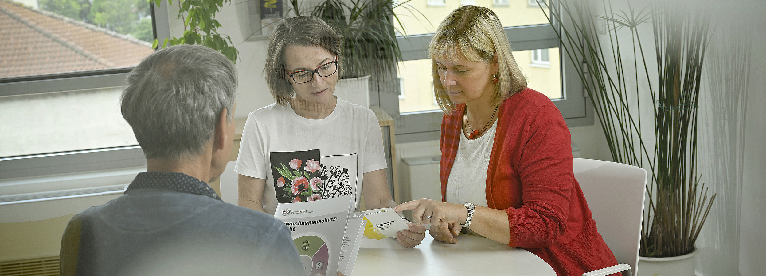 Erwachsenenvertreter im Beratungsgespräch an einem Tisch mit zwei Damen