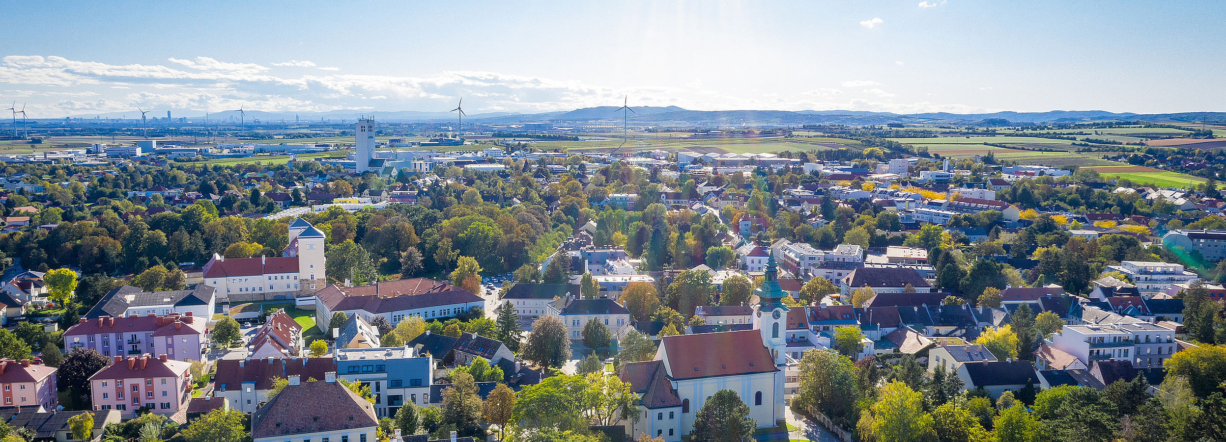 Erwachsenenvertretung in Niederoesterreich, VertretungsNetz. FC: iStock Foto von Niederösterreich: Luftaufnahme einer niederösterreichischen Kleinstadt mit markanter Kirche, dicht stehenden Wohnhäusern, vielen Bäumen und umliegenden Feldern in einer weitläufigen Landschaft.