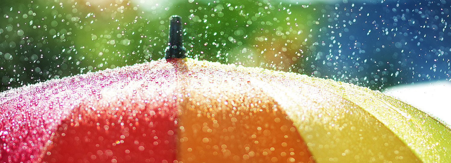 Foto: ein bunter Regenschirm, Regentropfen rundherum 