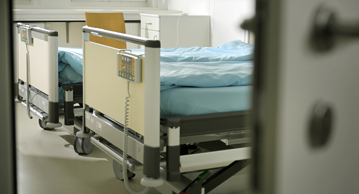 Foto: eine halboffene Tür, dahinter ein Zimmer in der Psychiatrie mit zwei leeren Betten