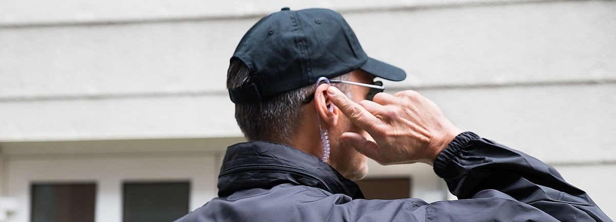 Foto: Security-Bediensteter in Uniform telefoniert über ein Headset