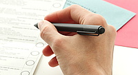 Wahlzettel, davor eine Hand, die einen Stift hält