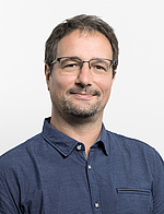 Philipp Martinak trägt kurze Haare und Brille sowie ein graublaues Hemd