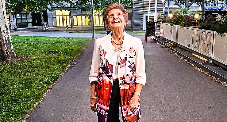 Porträt einer älteren Dame in eleganter Jacke und Perlenkette, die vor einem Straßencafé in Wien lächelt – symbolisch für ihr langjähriges Engagement als ehrenamtliche Erwachsenenvertreterin im Ehrenamt Wien.