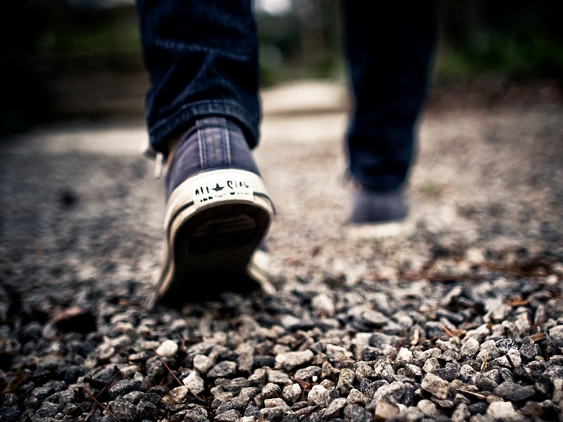 Foto: jemand geht eine steinige Straße entlang, man sieht nur die Beine
