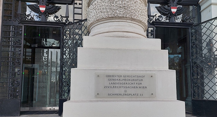 Haupteingang des OGH, große Steinsäule im Vordergrund mit Plakette. auf der "oberster Gerichtshof" steht